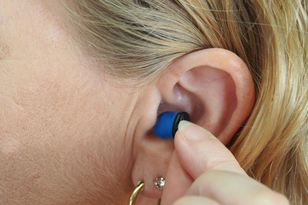 Woman placing earbud into her left ear